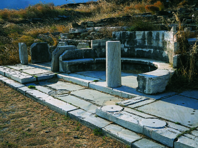 Αρχαία μαρμάρινα ερείπια με ημικυκλικό κάθισμα σε αρχαιολογικό χώρο