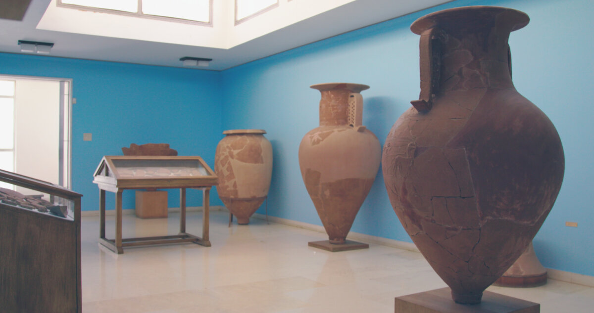 TINOS HANDMADE17 Αίθουσα αρχαιολογικού μουσείου με μεγάλα αρχαία πιθάρια σε γαλάζιο φόντο